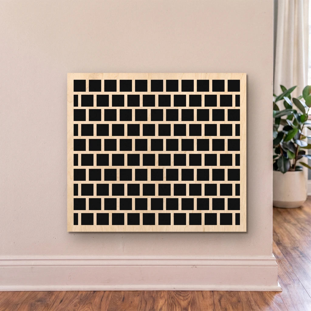 Decorative wall art with black square pattern on a light wood frame against a beige wall.