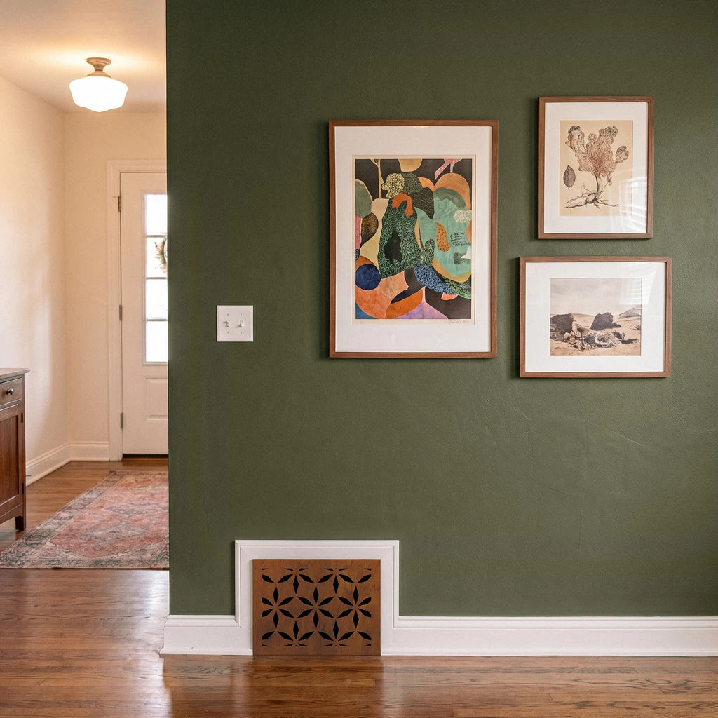 Three framed artworks on a green wall with wooden floor and door in the background