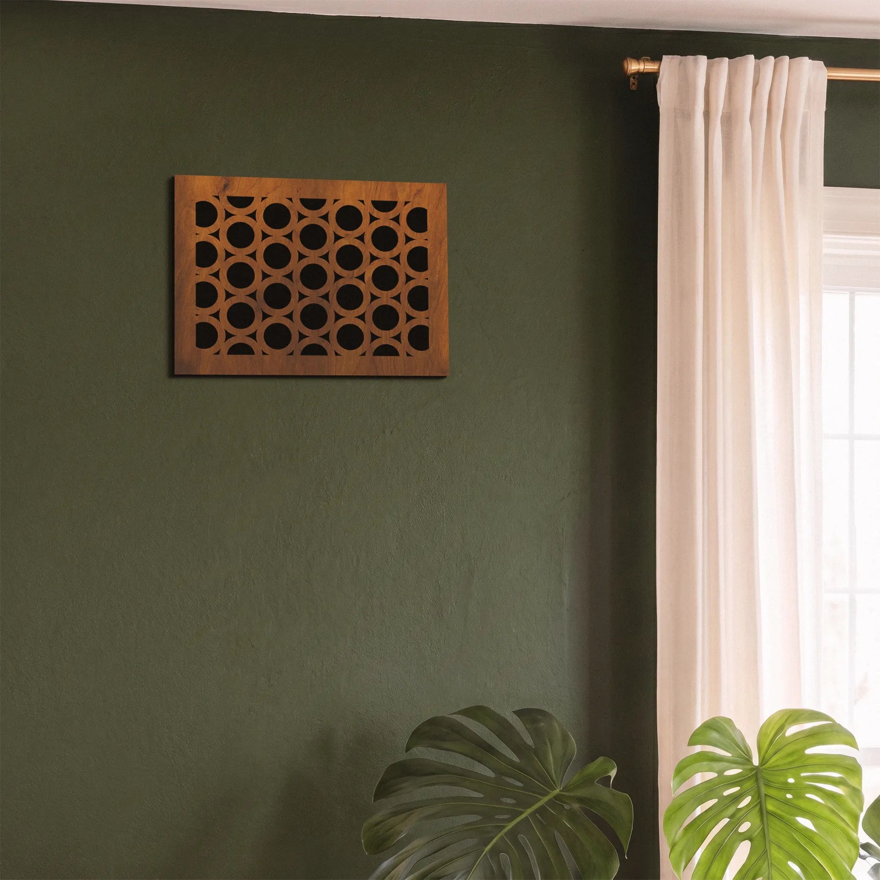 Decorative wooden wall art on a green wall with a window and plant in the background