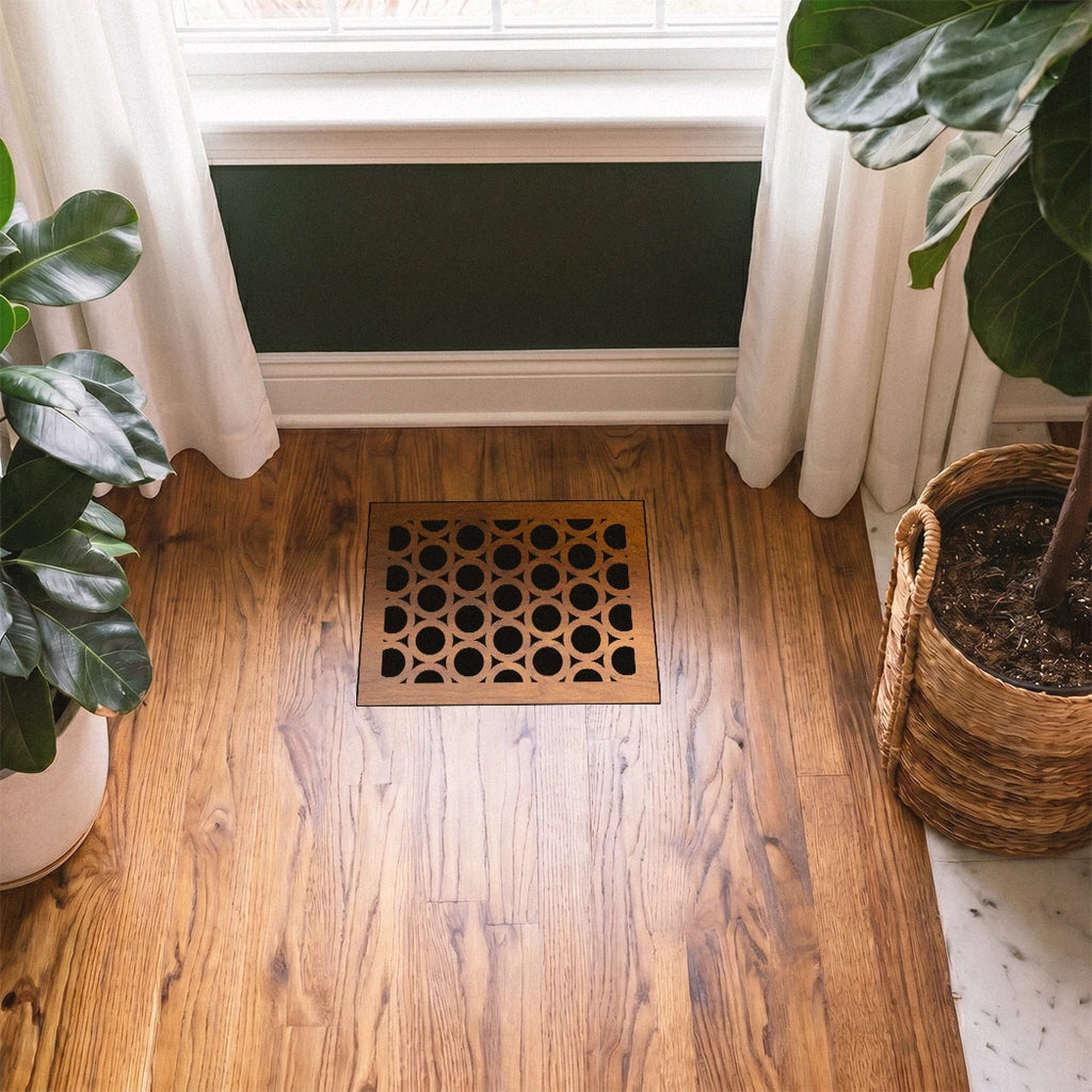 Decorative doormat with geometric pattern on a wooden floor, flanked by potted plants.