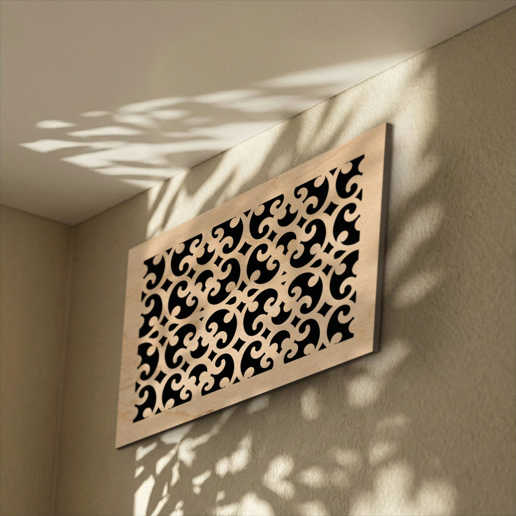 Decorative wall panel with intricate cut-out patterns on a beige wall.