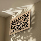 Decorative wall panel with intricate cut-out patterns on a beige wall.