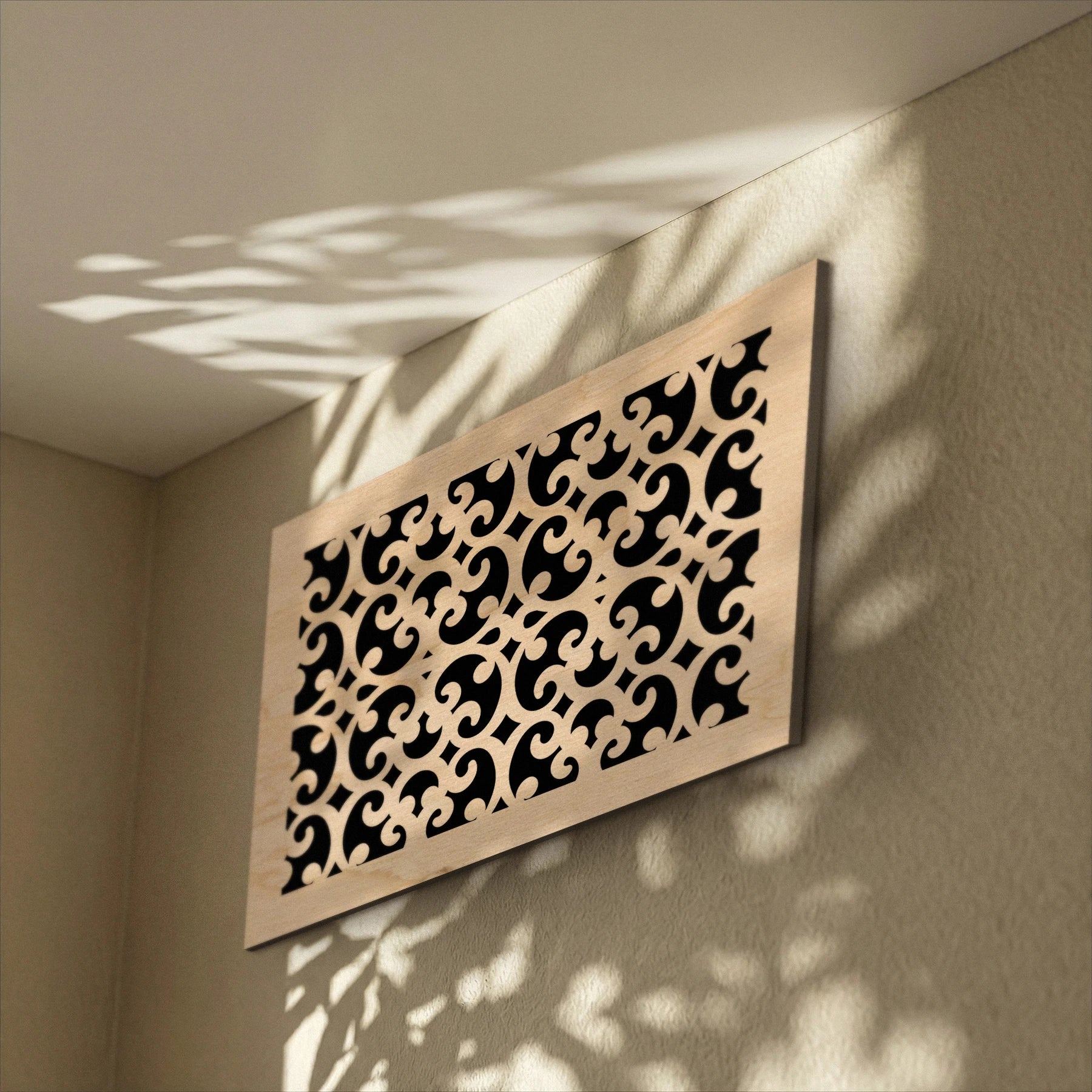 Decorative wall panel with intricate cut-out patterns on a beige wall.